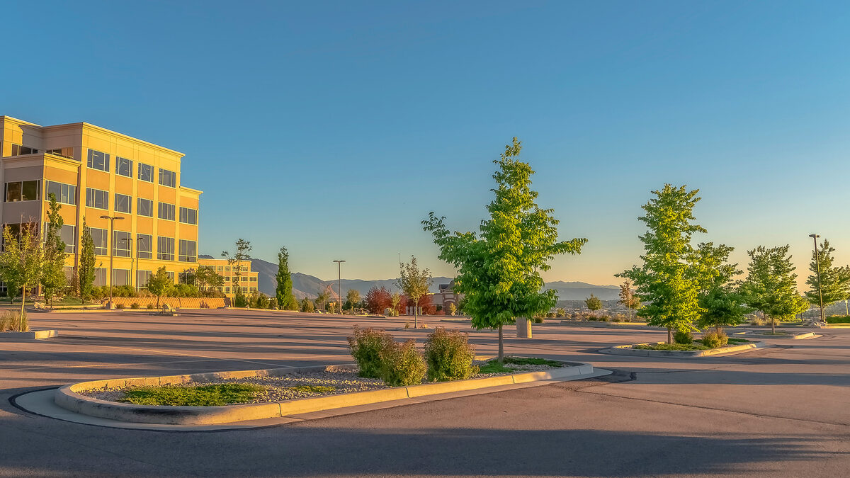 Low-rise office building with a landscaped parking lot on a clear day