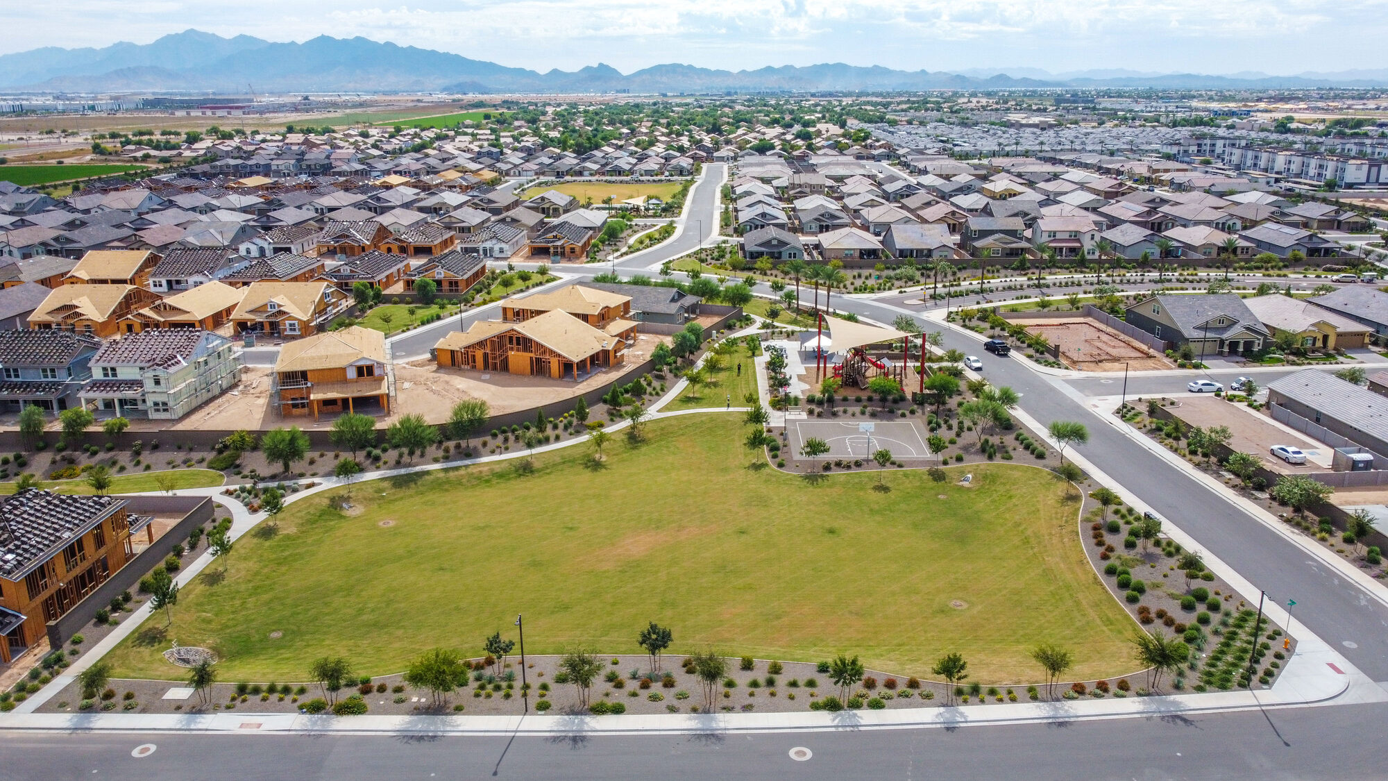 Aerial view of a new master-planned neighborhood with a park, desert mountains behind