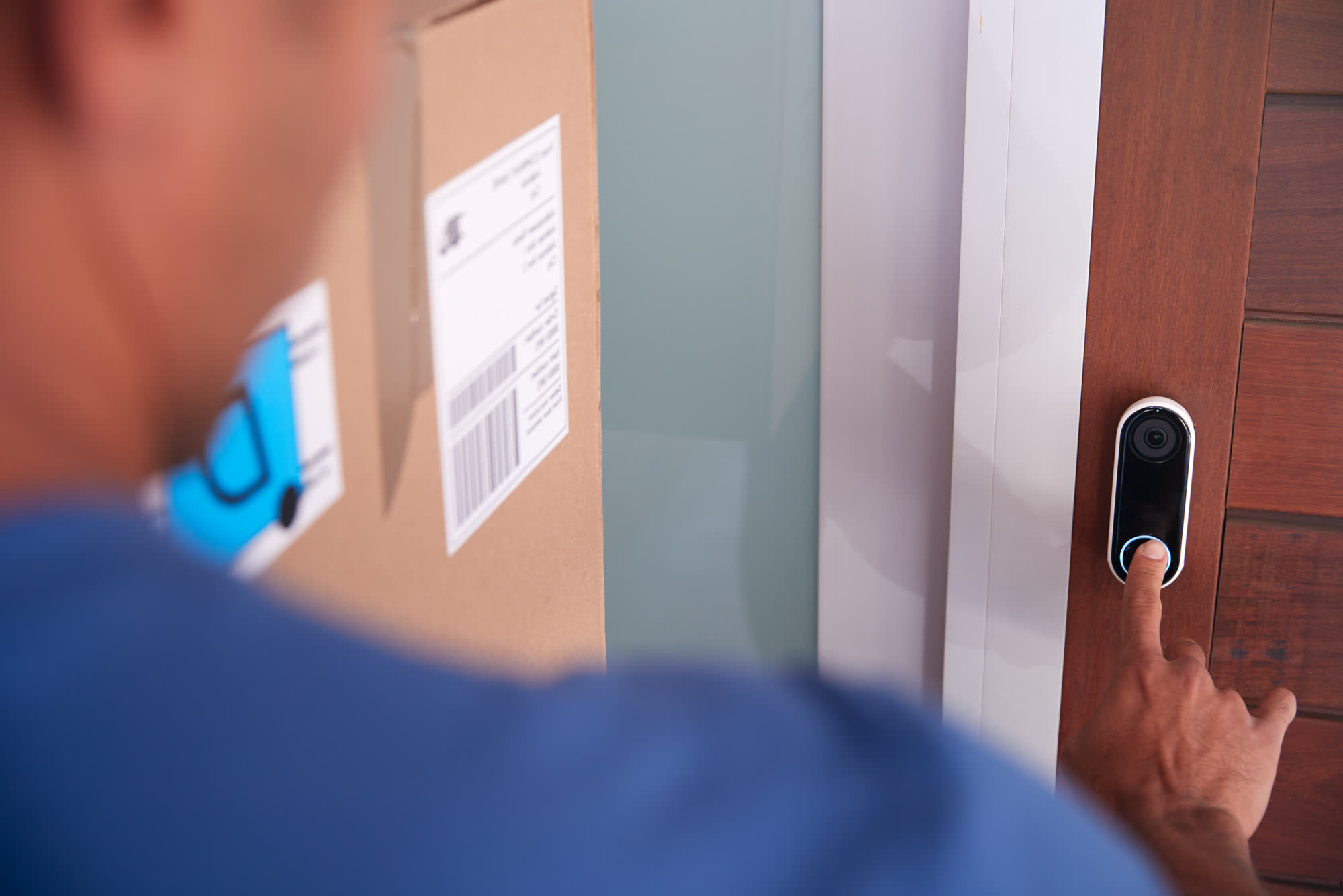 A visitor pressing a video doorbell at the front door