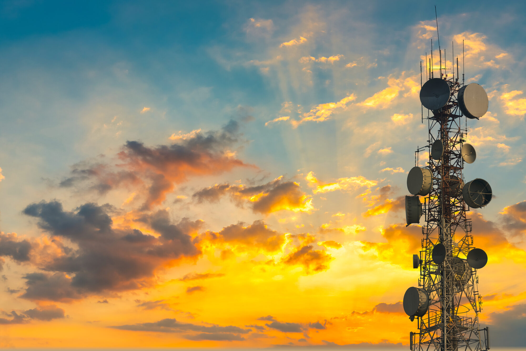 A wireless tower against a gold and blue sunset sky